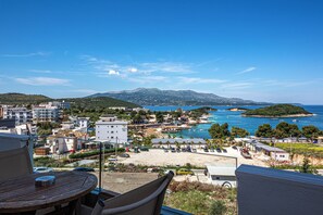 Un balcón con vistas a un pueblo costero, que incluye edificios, una playa y el mar.