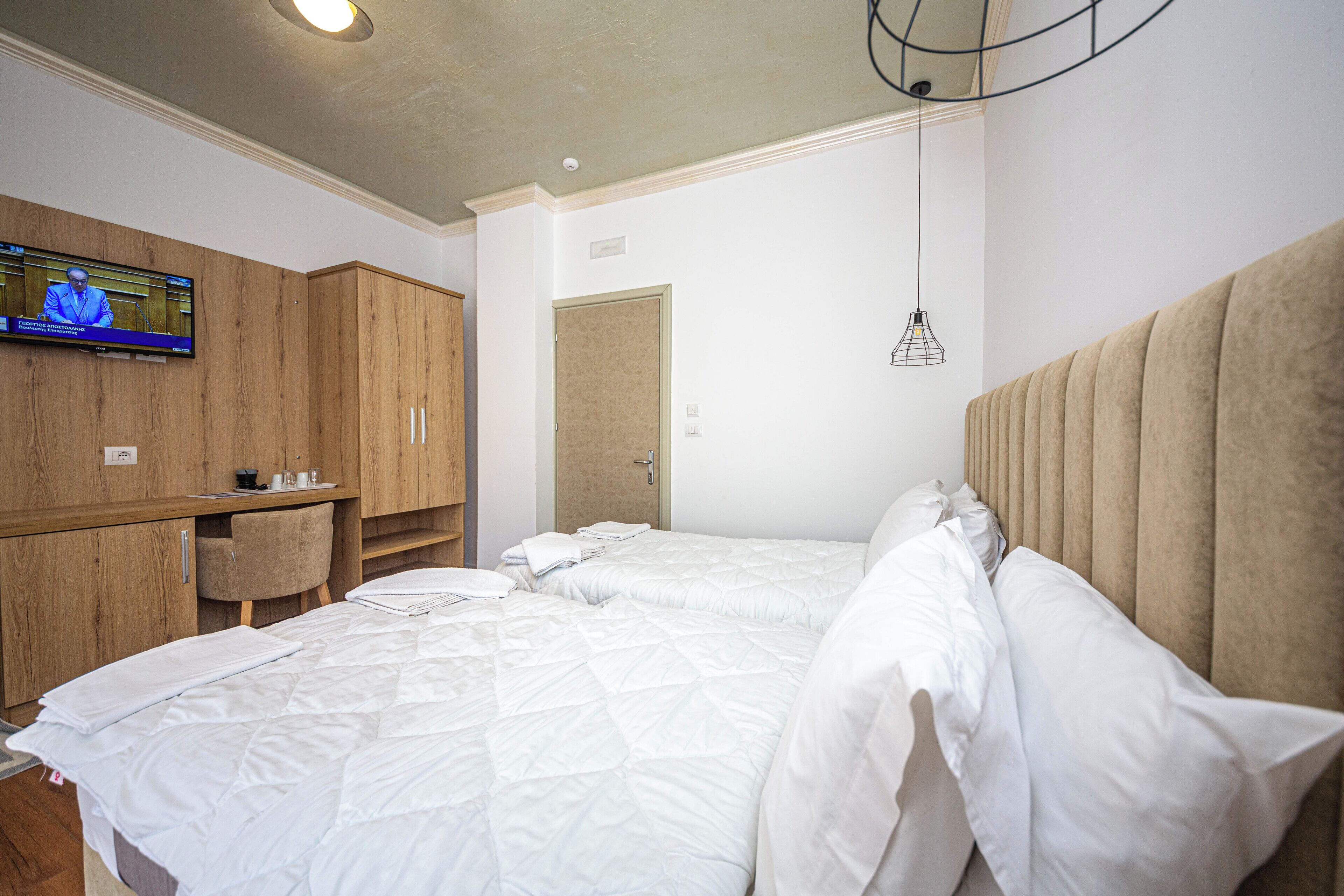 Una camera d'albergo con un letto grande, una televisione a muro, mobili in legno e un lampadario.