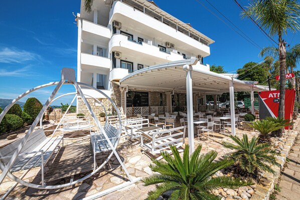 A multi-story hotel with outdoor seating and a covered patio area. - Hotel Murati (Ksamil)