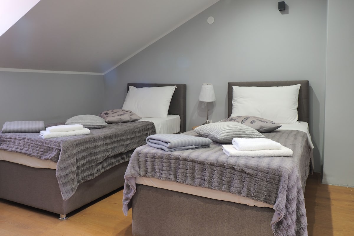 Ein Zimmer mit zwei Betten, jeweils mit Kopfteil, Kissen und Decken.