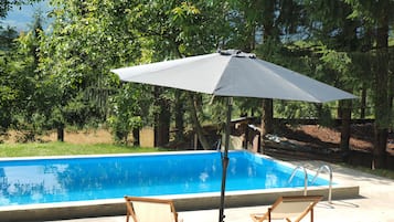 Una piscina al aire libre, sombrillas, sillones reclinables de piscina