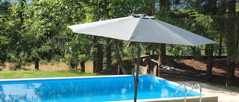 Una piscina al aire libre, sombrillas, sillones reclinables de piscina