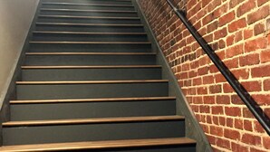 A staircase with wooden steps and a brick wall on one side.