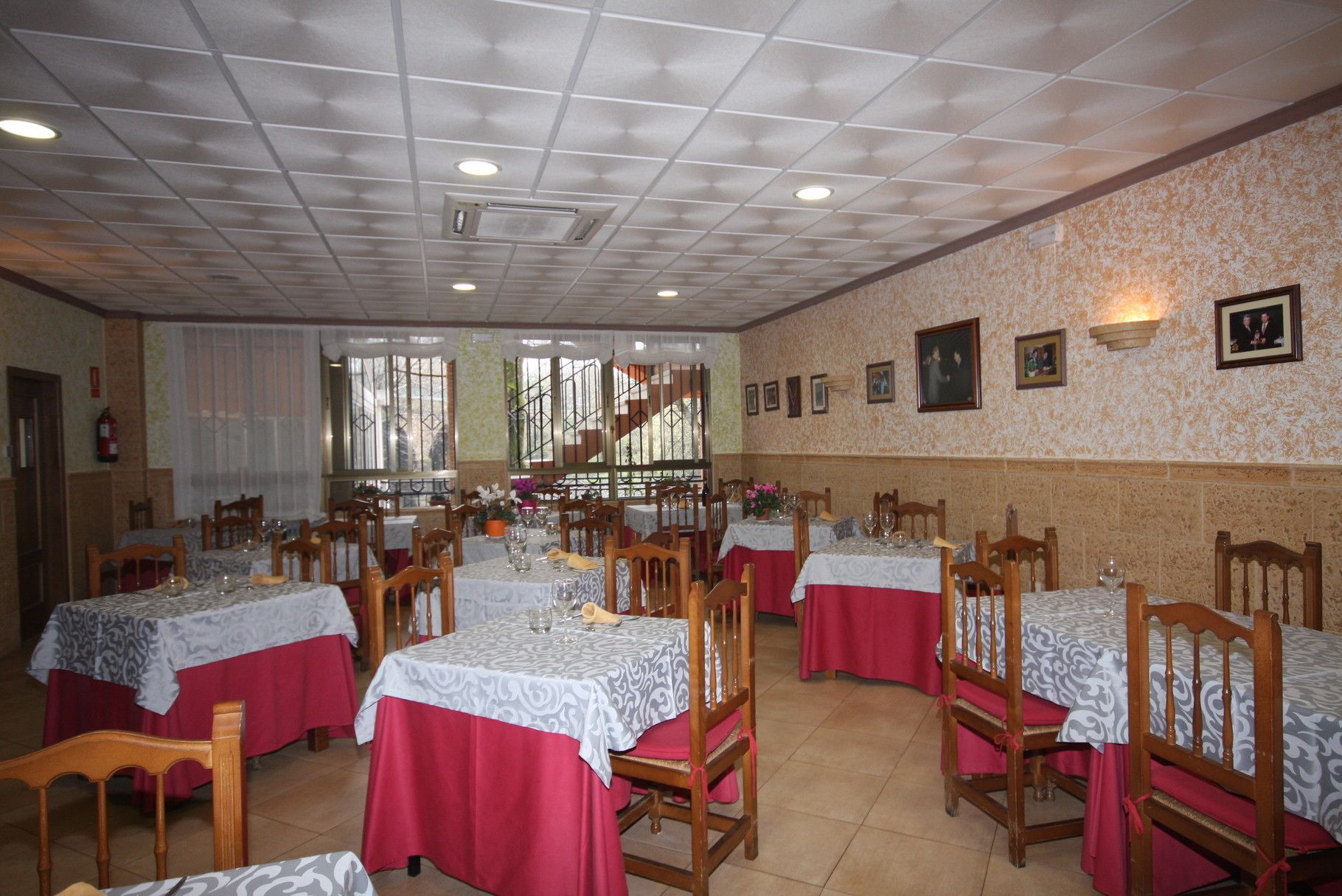 A dining area with tables set for multiple people, chairs, and a staircase in the background.