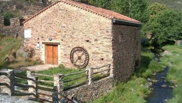 Un edificio de piedra con una puerta de madera y un reloj grande en la pared.