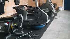 A fitness center with exercise equipment, wooden walls, and a door. -  Thomas' Store- Remodeled in Oct 2021, pet friendly (Steinhatchee)
