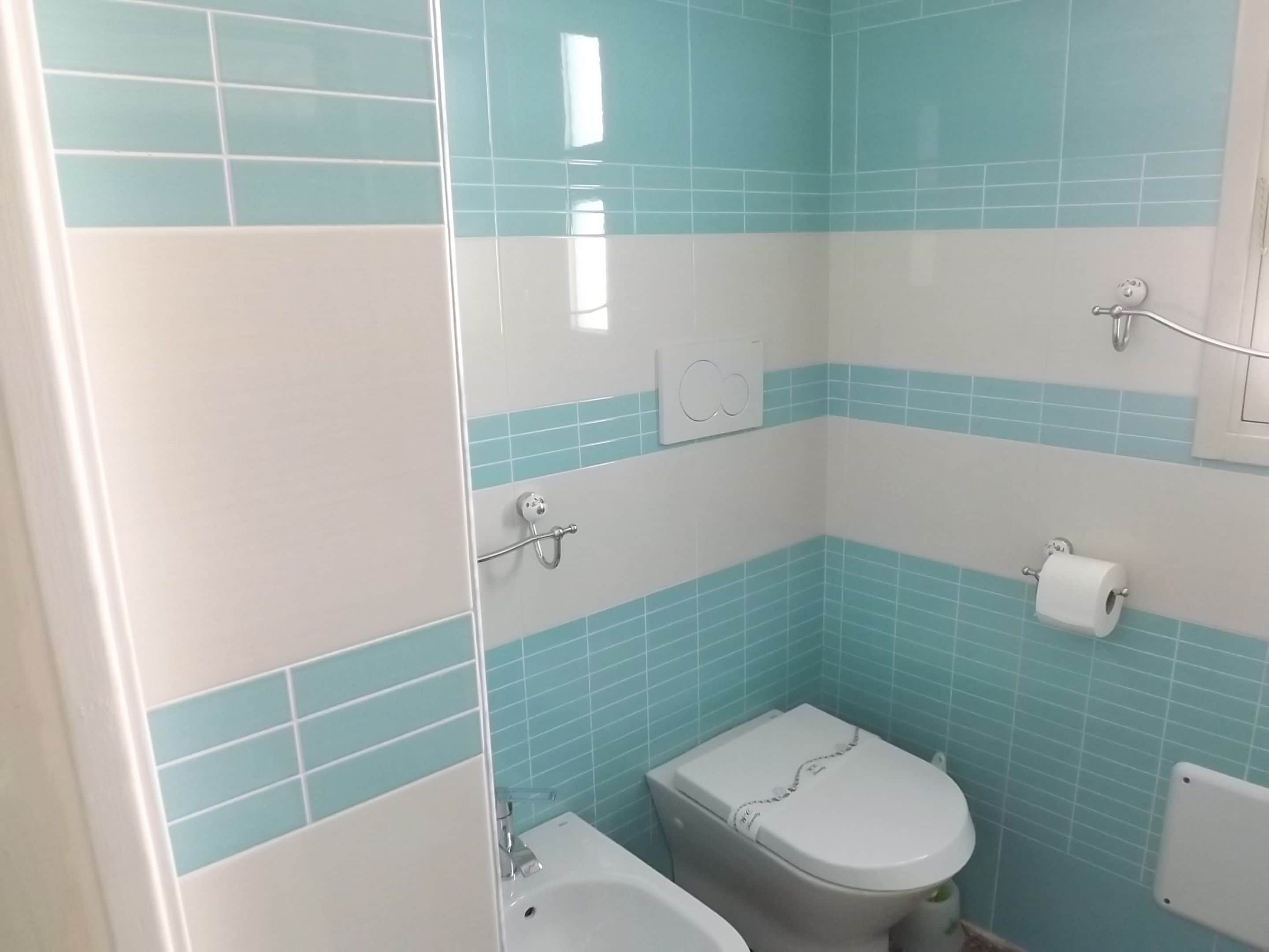 Un baño con inodoro, bidé y toallero.
