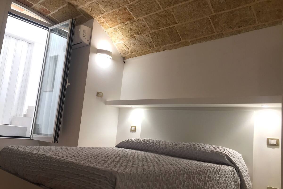 A bedroom with a bed, a window, and a brick ceiling.
