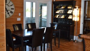 Un intérieur en bois comprenant une table à manger, des chaises, une horloge et une bibliothèque.