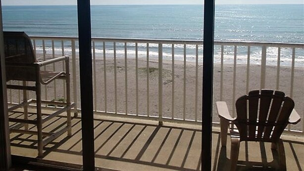 Een balkon met uitzicht op het strand en de oceaan.