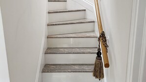 Un escalier avec des rampes en bois et un tapis de couleur sombre au bas.
