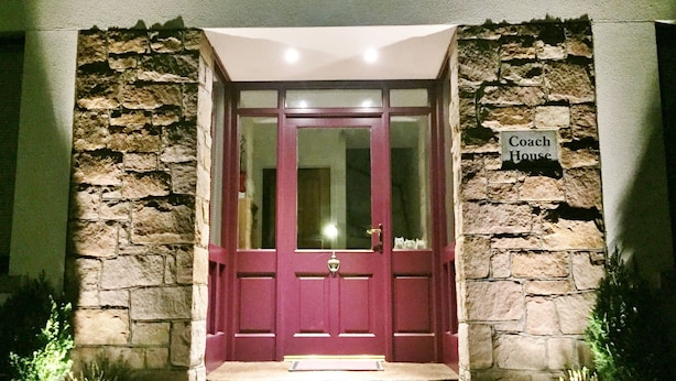 Une façade en pierre avec une porte rouge et une enseigne indiquant « Coach House ».