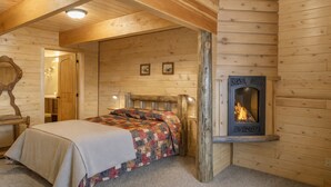 Une chambre confortable dans un chalet en bois, avec un lit, une cheminée et un miroir au mur.