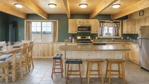 Une cuisine spacieuse avec des meubles en bois, un grand îlot central doté de tabourets, un four à micro-ondes, un four traditionnel et un réfrigérateur.