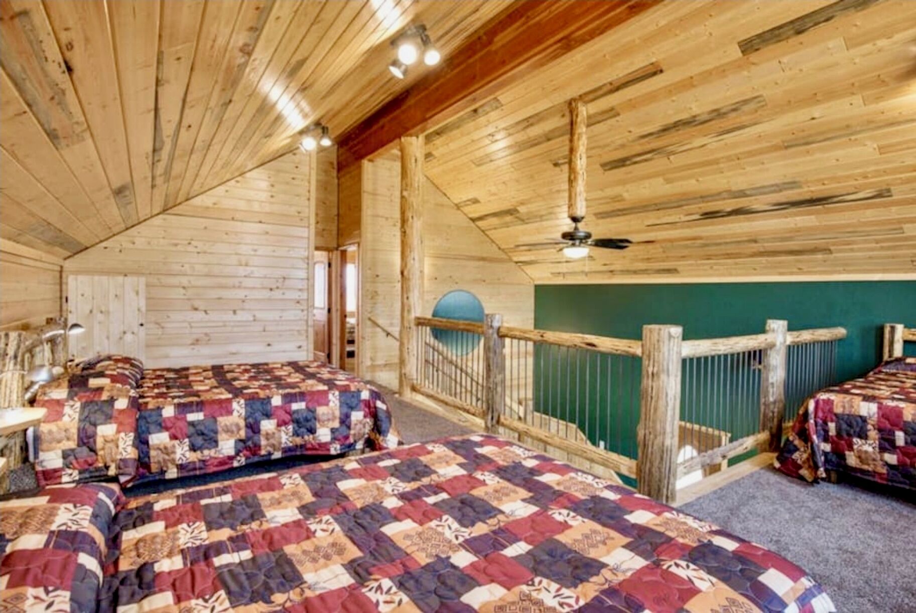 A cabin with two beds, wooden walls, a balcony with a railing, and a ceiling fan.