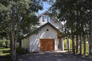 A two-story house with a large garage, surrounded by trees.