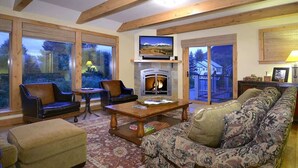A cozy living room with a fireplace, comfortable seating, and large windows.