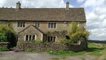 A stone house with a tiled roof, multiple windows, and a stone wall surrounding the property.