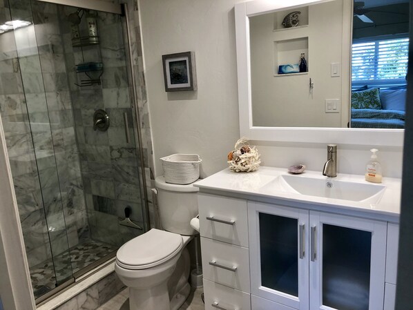 A bathroom with a glass-enclosed shower, a toilet, a sink with a mirror, and a cabinet with drawers. - Stunning Nature! Waterfront! Prime Fishing! Bring Boat. Free Bikes, SUP, Kayak. (Bokeelia)