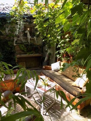 Un jardin intérieur accueillant, avec un coin salon doté de coussins moelleux, une petite table et diverses plantes.