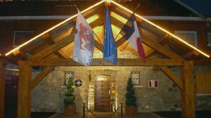 A stone building with a wooden roof and flags hanging from it. - Le Chalet d'Auron (Saint-Etienne-de-Tinee)
