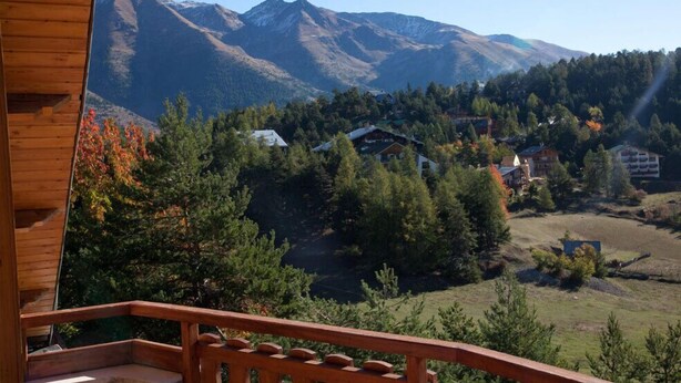 A wooden cabin with a balcony overlooking a mountainous landscape with houses and trees. - Le Chalet d'Auron (Saint-Etienne-de-Tinee)