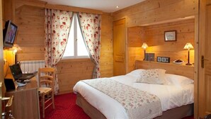 A wooden cabin-style room with a bed, desk, chair, and two lamps. - Le Chalet d'Auron (Saint-Etienne-de-Tinee)