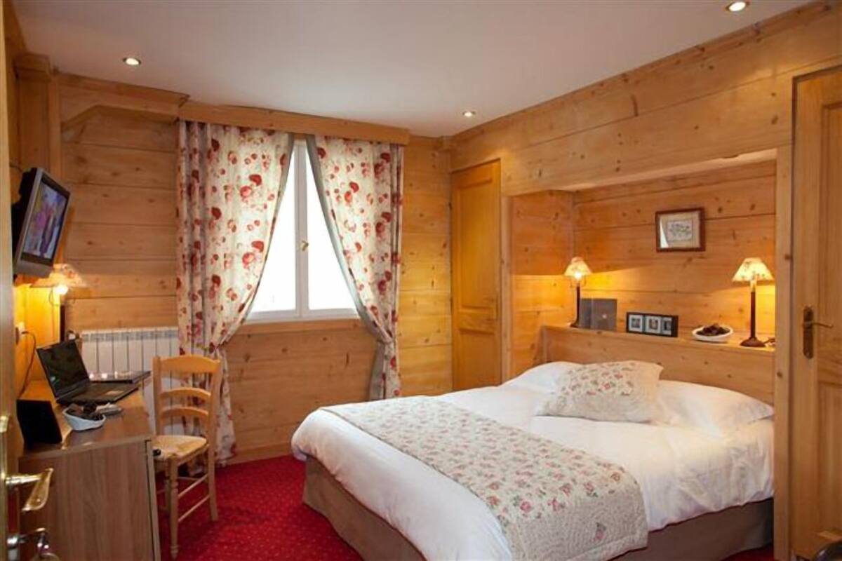 Une pièce aménagée comme un chalet en bois, avec un lit, un bureau, une chaise et deux lampes.