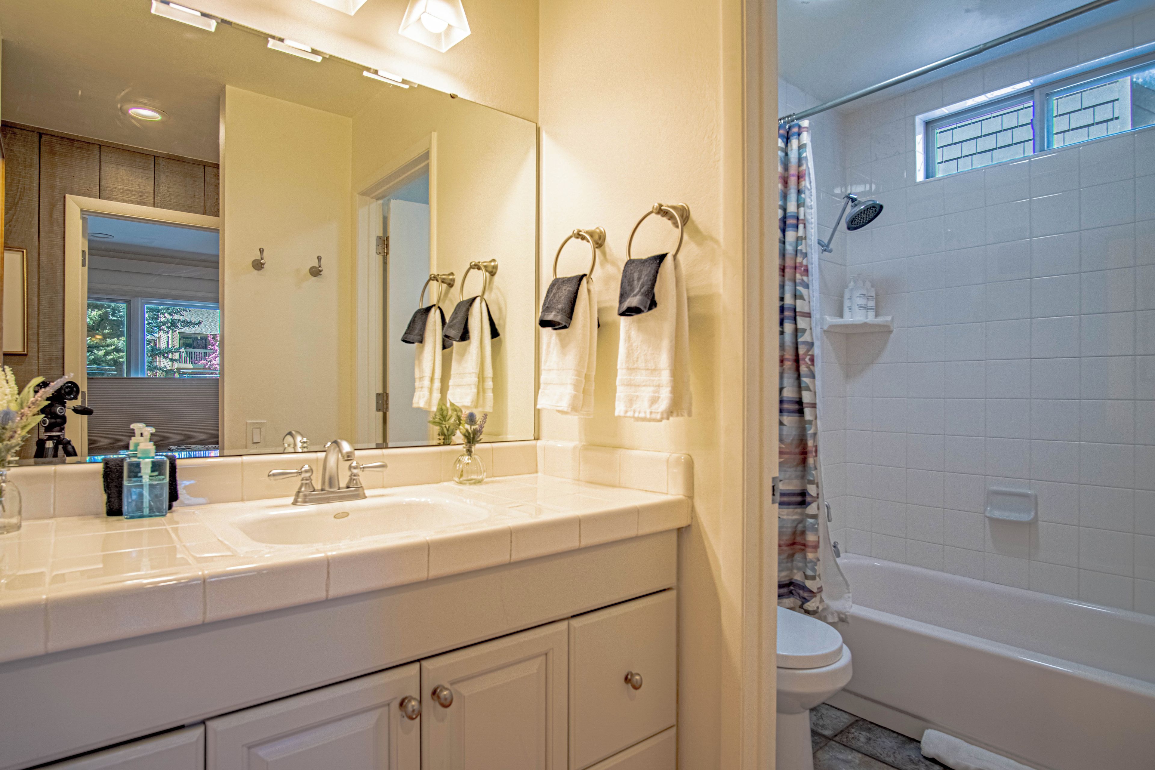 Une salle de bain avec un lavabo blanc, un miroir et une baignoire.