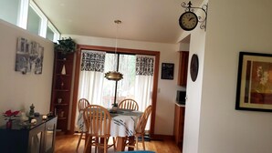 A dining area with a table and chairs, a clock, and a framed picture on the wall. - Beautiful Home with Traditional & Modern Ambience (Edmonds)