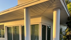 Een modern huis met een overdekte veranda, grote ramen en een tuin.