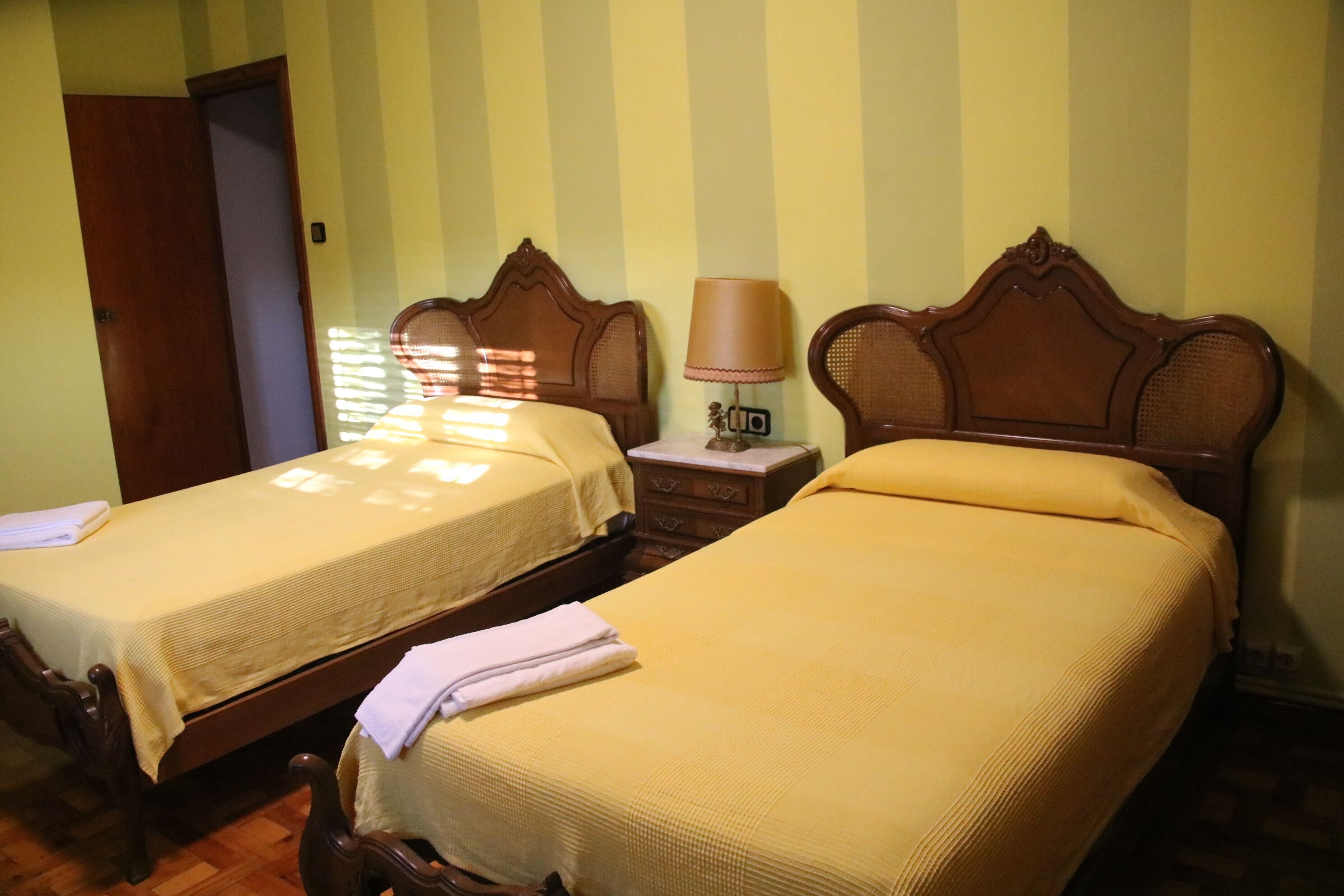 Two single beds with wooden headboards and a bedside table with a lamp.