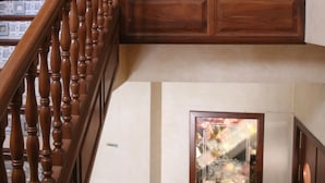 Una escalera de madera con barandilla, un extintor y obras de arte enmarcadas en las paredes.