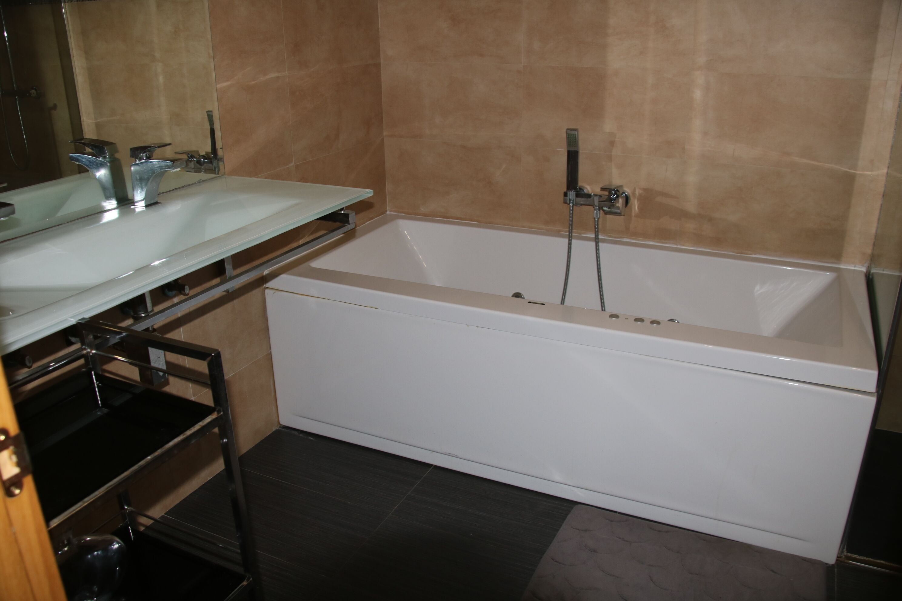 Un baño con una bañera blanca, un tocador de vidrio y una zona de ducha.
