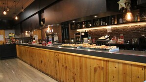 Una barra con alimentos, suelo de madera y pared de ladrillo al fondo.