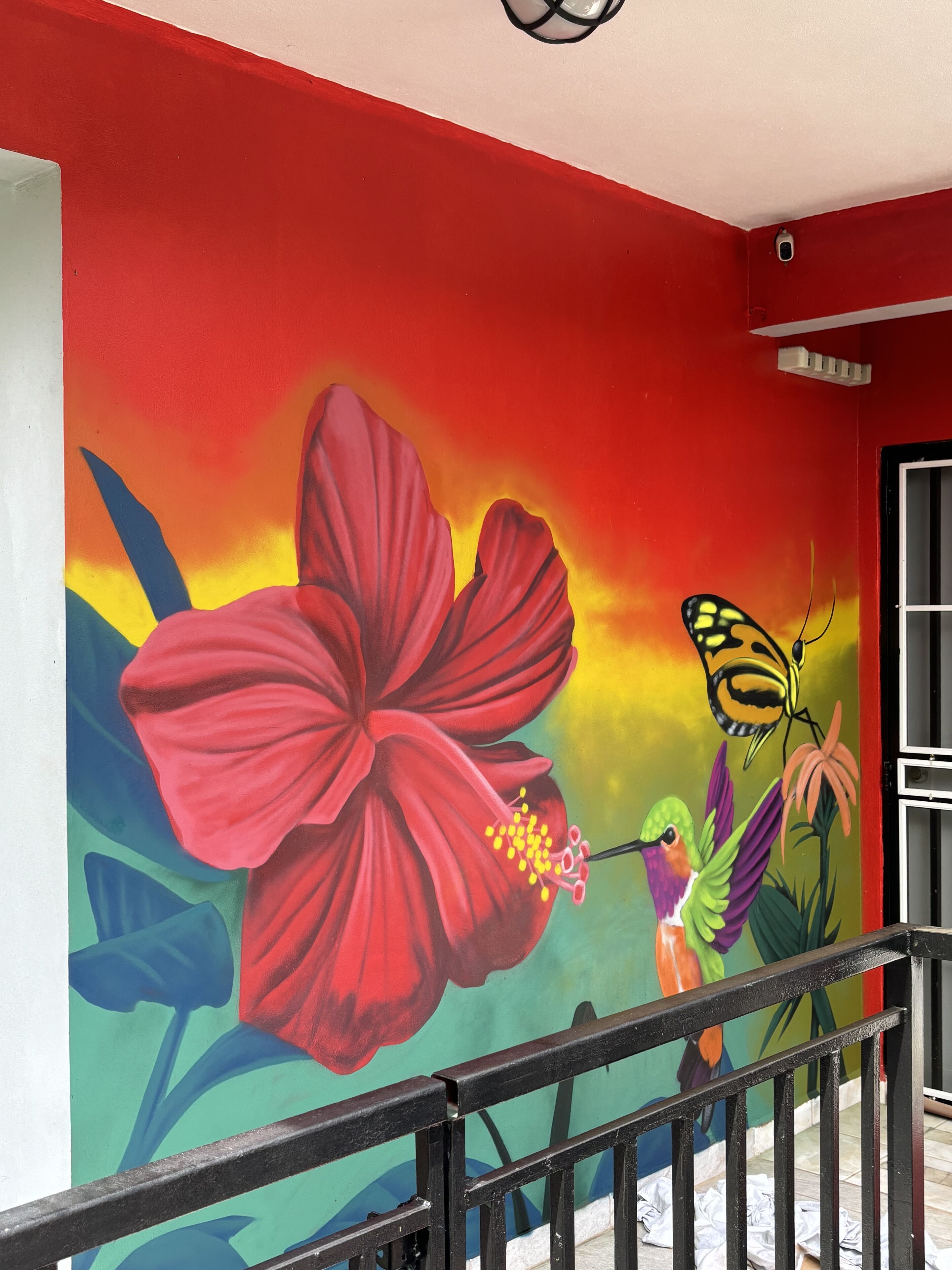 A vibrant mural with a large red flower, a hummingbird, and a butterfly.