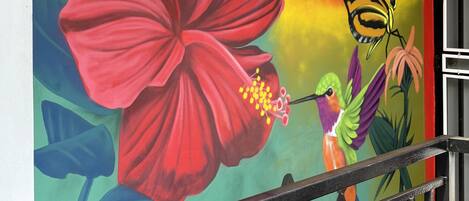 A vibrant mural with a large red flower, a hummingbird, and a butterfly.