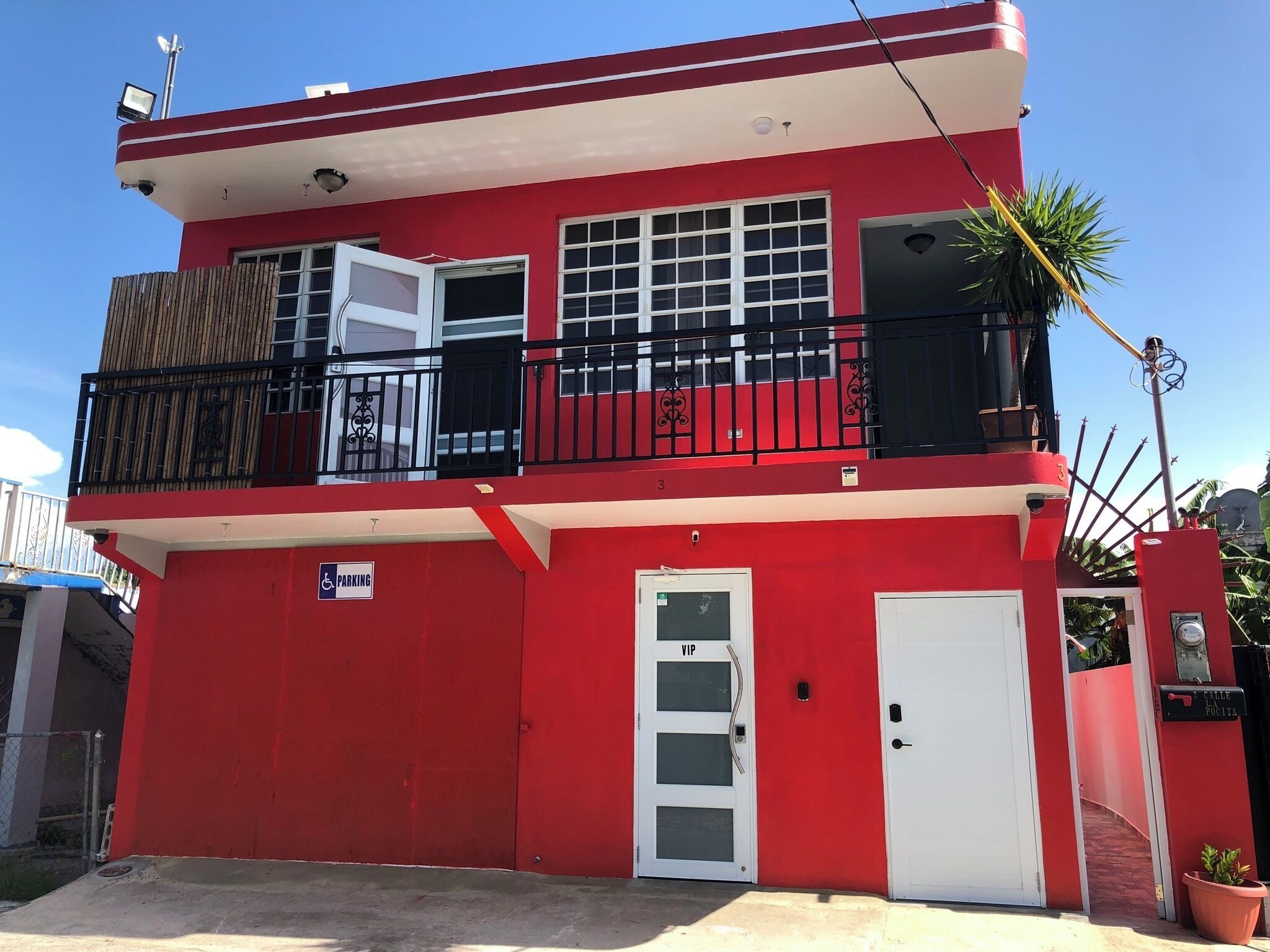Un bâtiment rouge avec une porte blanche, un balcon et un panneau indiquant un espace de stationnement réservé aux VIP.