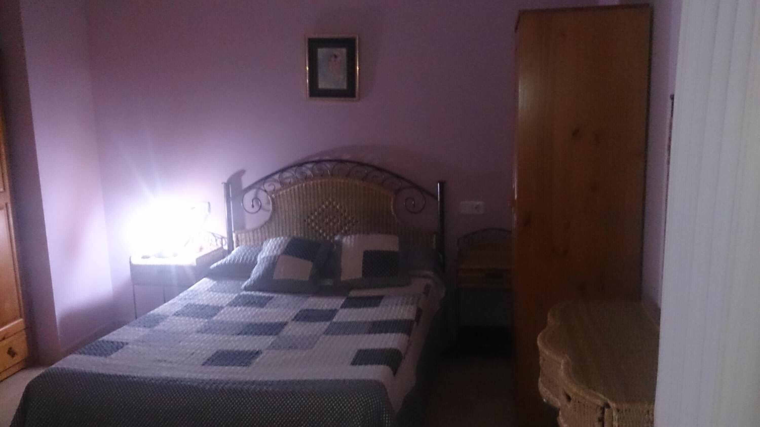 Un dormitorio con una cama, un armario de madera y una mesita pequeña.