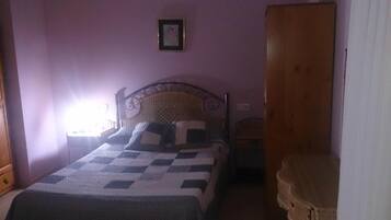 Un dormitorio con una cama, un armario de madera y una mesita pequeña.