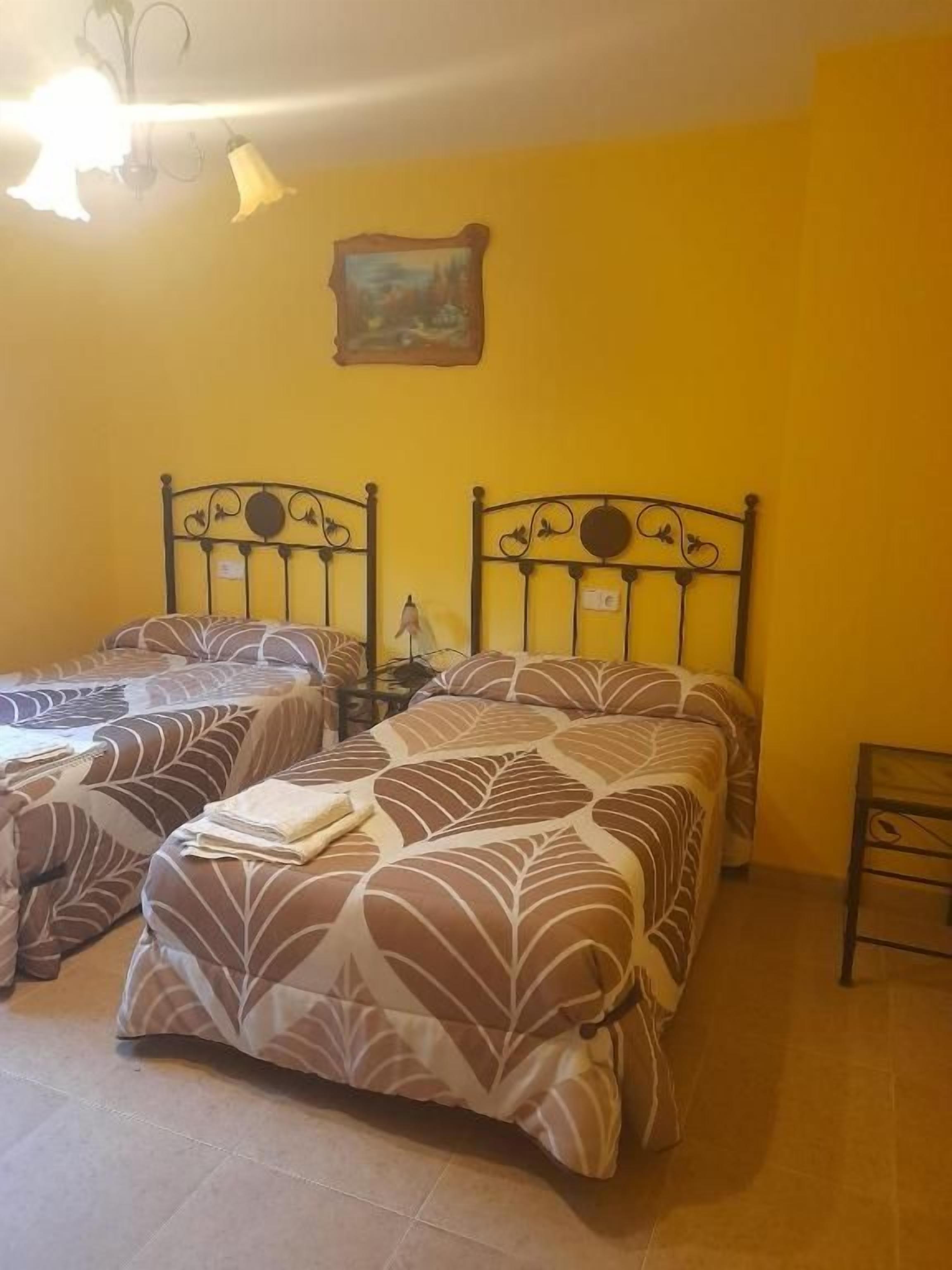 Una habitación con dos camas, una mesita y un cuadro en la pared.