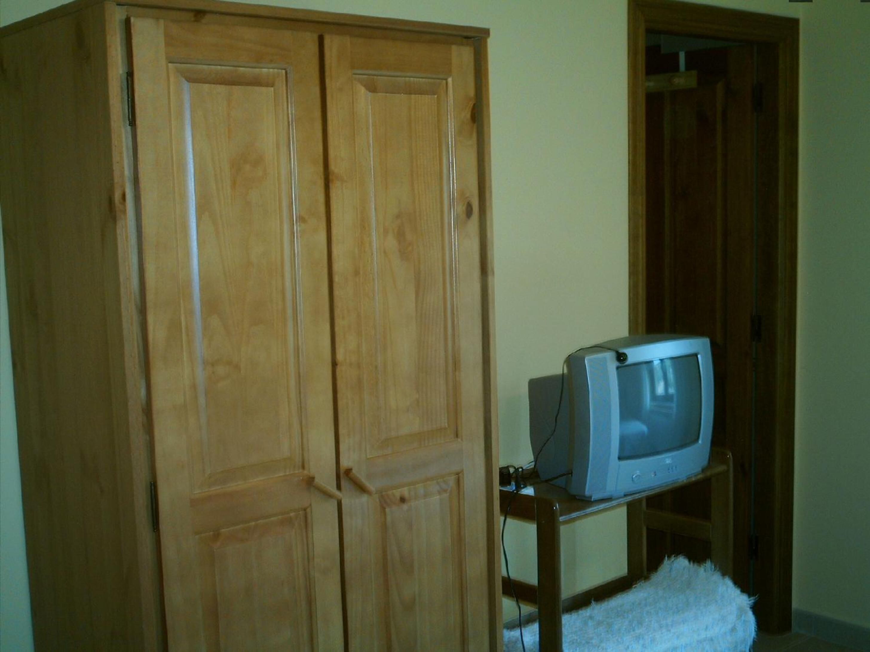 Een houten garderobe met een televisie op een standaard.