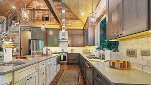 Una cocina moderna con una isla central, electrodomésticos de acero inoxidable y un techo de madera rústica.