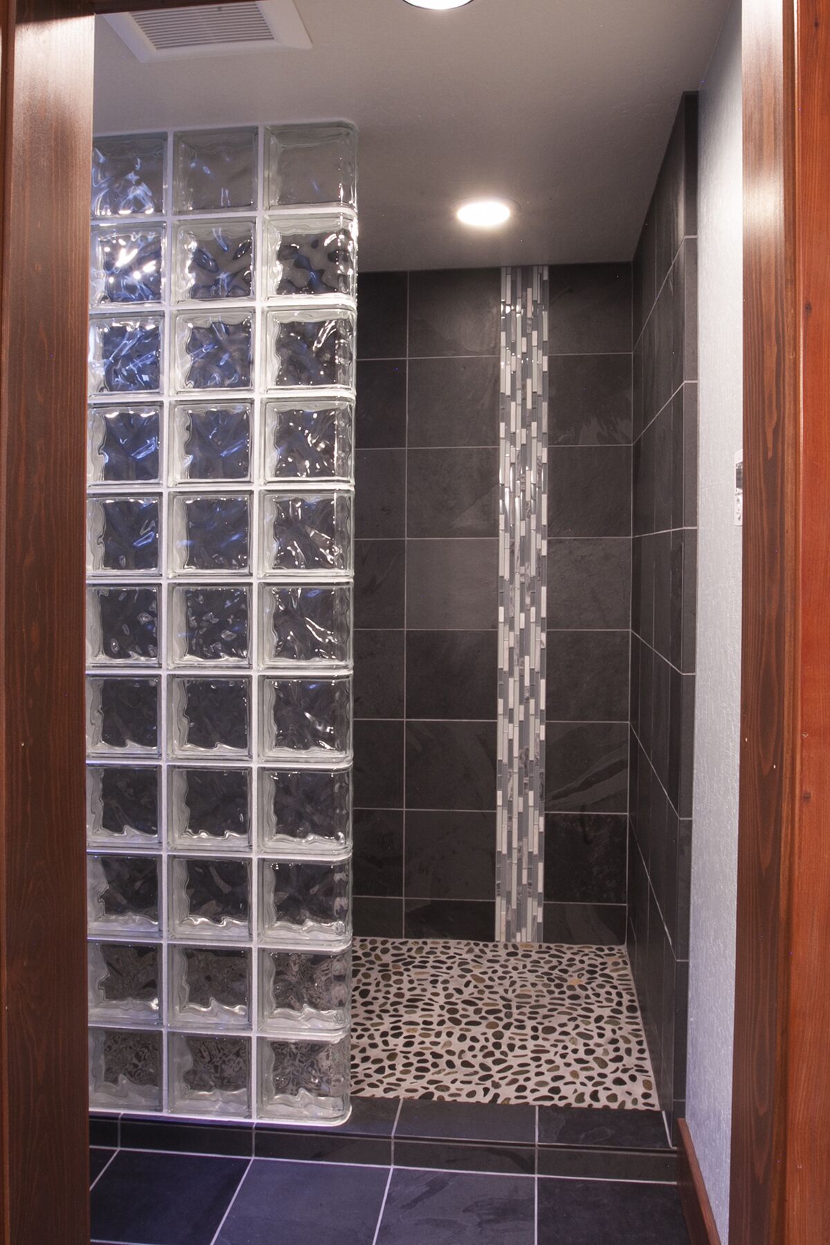 A shower with a glass partition and a patterned floor.