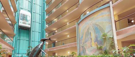 A spacious atrium with a central sculpture, multiple floors, and a large mural.