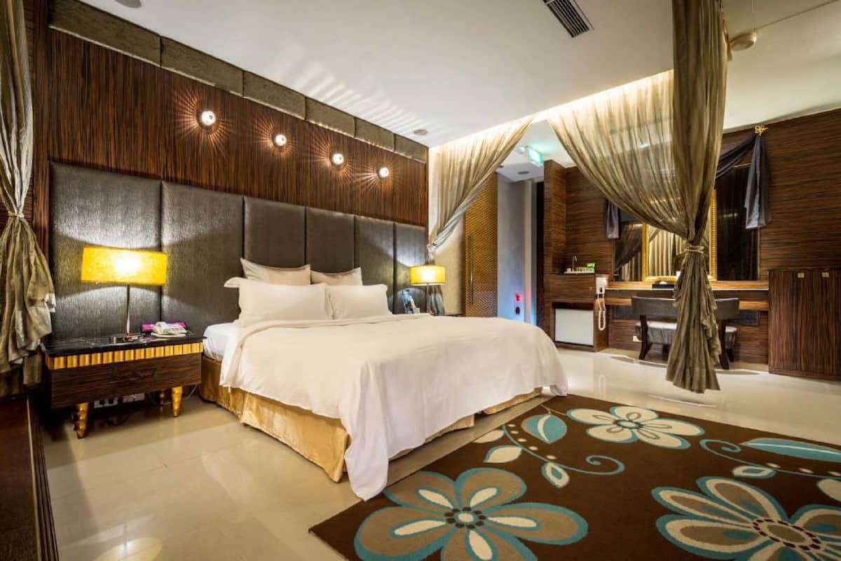 A hotel room with a large bed, nightstands, a desk, and a bathroom.