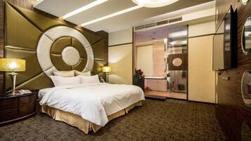 A hotel room with a large bed, a bedside table with a lamp, a mirror, and a view of a bathroom with a bathtub.