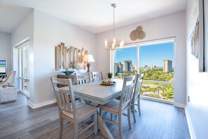 Un comedor con una mesa grande, sillas y vistas a la ciudad a través de amplios ventanales.
