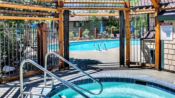 A swimming pool with a metal ladder, surrounded by a wooden pergola and a fence. - Clean and fresh remodeled Lake Forest Glen End Unit (Tahoe City)