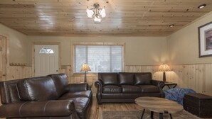 A living room with two leather sofas, a wooden coffee table, and a large window with blinds. - Clean and fresh remodeled Lake Forest Glen End Unit (Tahoe City)